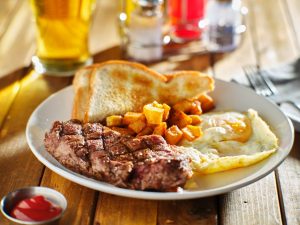 steak and eggs breakfast with toast and homestyle potatoes in restaurant